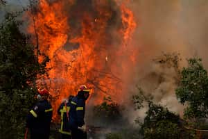 Los bomberos intentan extinguir las llamas en el pueblo de Ellinika en la isla de Evia, a unos 176 kilómetros (110 millas) al norte de Atenas, Grecia, lunes, 9 de agosto, 2021. Los bomberos y residentes lucharon contra un gran incendio forestal en la segunda isla más grande de Grecia por séptimo. El lunes del día, luchando para salvar lo que pueden, de las llamas que han diezmadas grandes extensiones de bosques prístinos, destruyen hogares y negocios, y han enviado miles de personas que huyen. (AP Foto / Petros Karadjias)