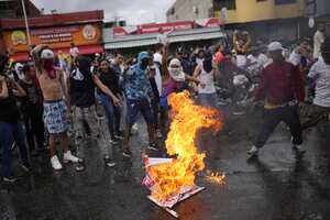 Los manifestantes queman un cartel de campaña electoral del presidente Nicolás Maduro mientras se manifiestan contra los resultados oficiales de las elecciones que lo declaran ganador el día después de los comicios en Caracas, Venezuela, el lunes 29 de julio de 2024. (AP Foto/Matías Delacroix)