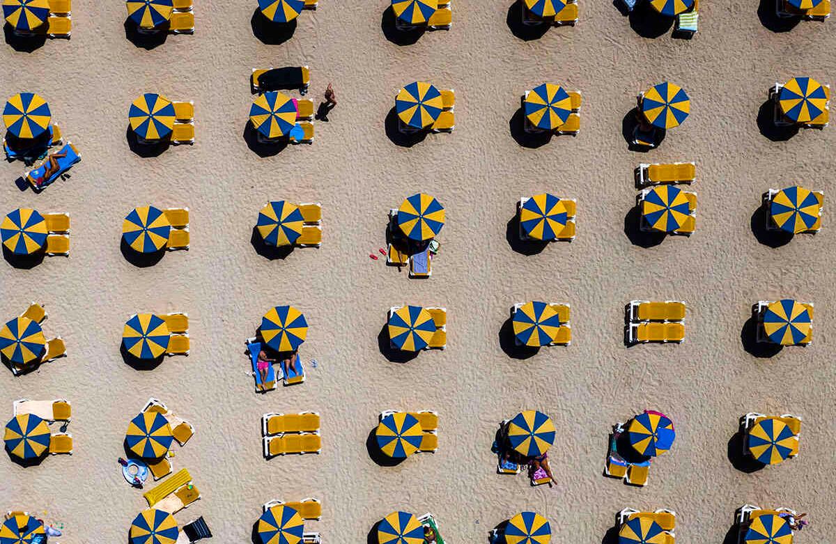 Los bañistas se relajan bajo las sombrillas en una playa en el suroeste de la isla de Gran Canaria, España, el miércoles 19 de agosto. Las autoridades españolas han anunciado nuevas restricciones para prevenir más contagios de coronavirus. Foto: Emilio Morenatti /AP 