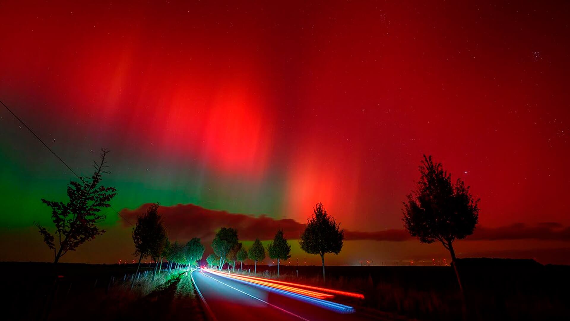 Una aurora boreal, también conocida como luces del norte, brilla en el cielo nocturno sobre una carretera en Lietzen, en el este de Alemania.