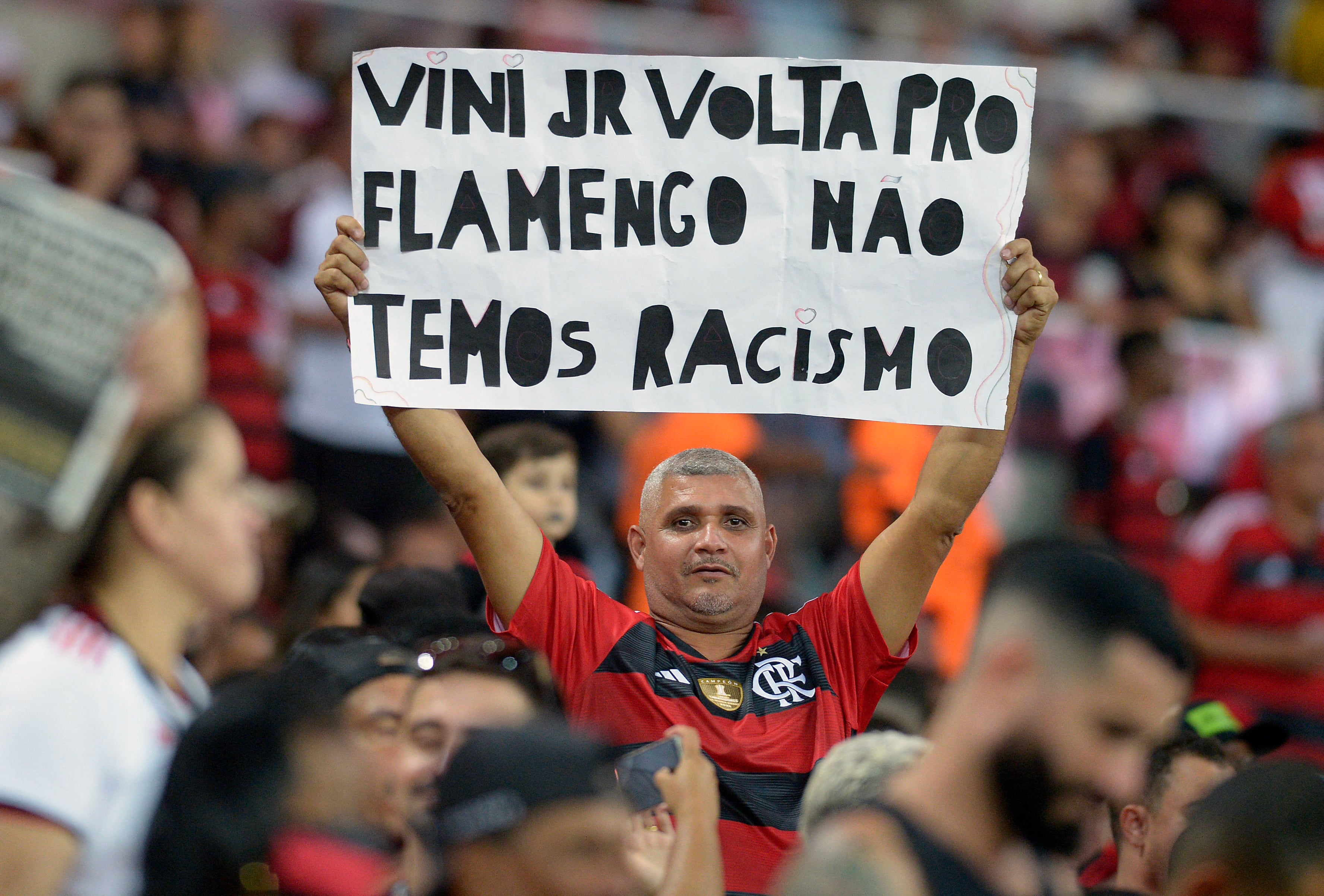 A supporter of Flamengo holds a sign reading �Vini Jr come back to Flamengo, we have no racism� in support of Brazilian player Vinicius Junior during a match of the 2023 Brazilian Championship between Flamengo and Cruzeiro at the Maracana stadium in Rio de Janeiro, Brazil, on May 27, 2023. Vinicius, the 22-year-old Real Madrid's superstar, was targeted with shouts of "monkey" from the stands last week -- the latest in a series of racist attacks against him. (Photo by DHAVID NORMANDO / AFP)