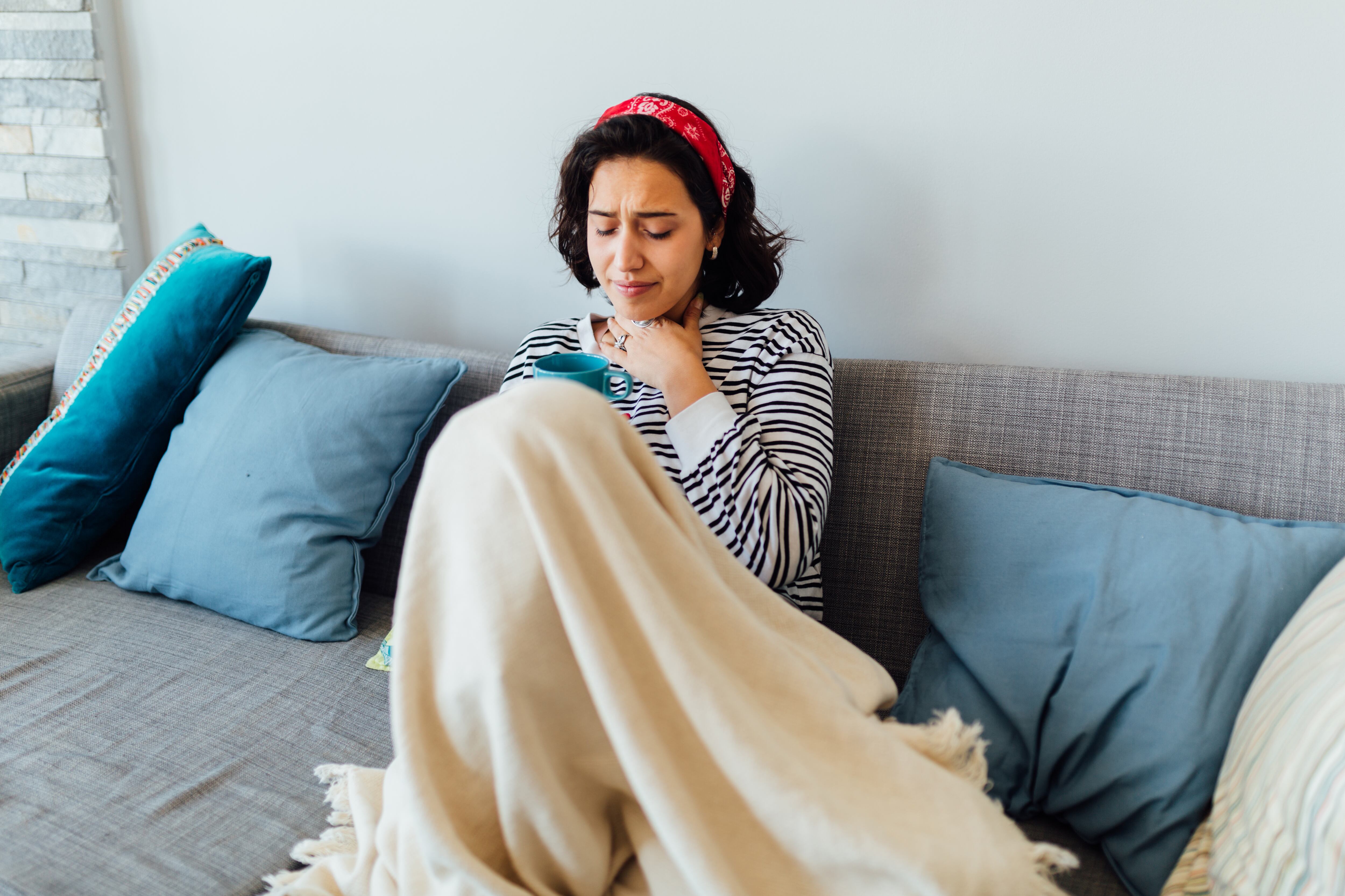 Young Caucasian woman staying at home due to her being sick, staying in quarantine and pushing through the corona virus symptoms