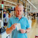 Close up color image depicting a mid adult man checking his groceries bill in the supermarket after making his purchases at the checkout. Focus on the man with the supermarket checkout defocused in the background. The man is wearing a casual blue polo shirt and has a worried expression on his face.