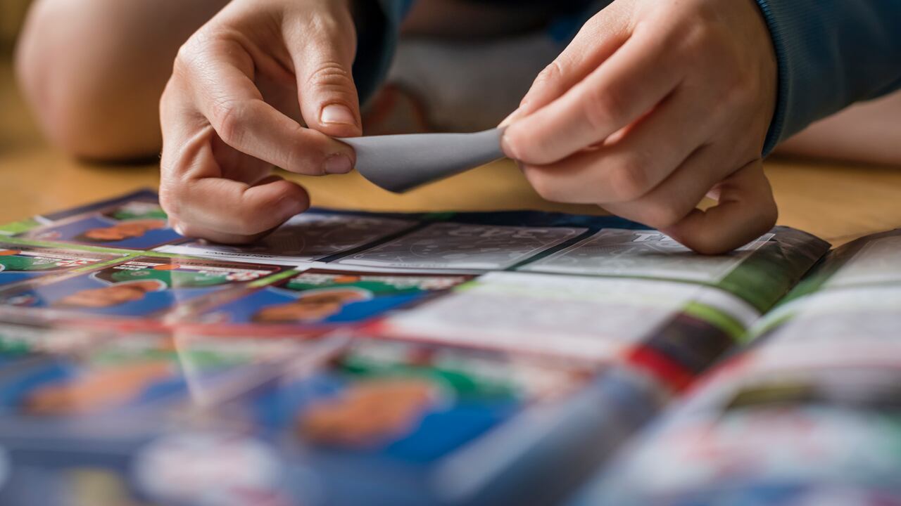 Zurich, Switzerland - April 16, 2016: An 8 year old boy is sitting on the floor of his room and is pasting football trading cards into his sticker collection scrapbook for the UEFA Euro 2016 Euopean football championship.