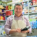 Propietario de negocio en una tienda local con un lector de tarjetas de crédito, utilizando conceptos de tecnología