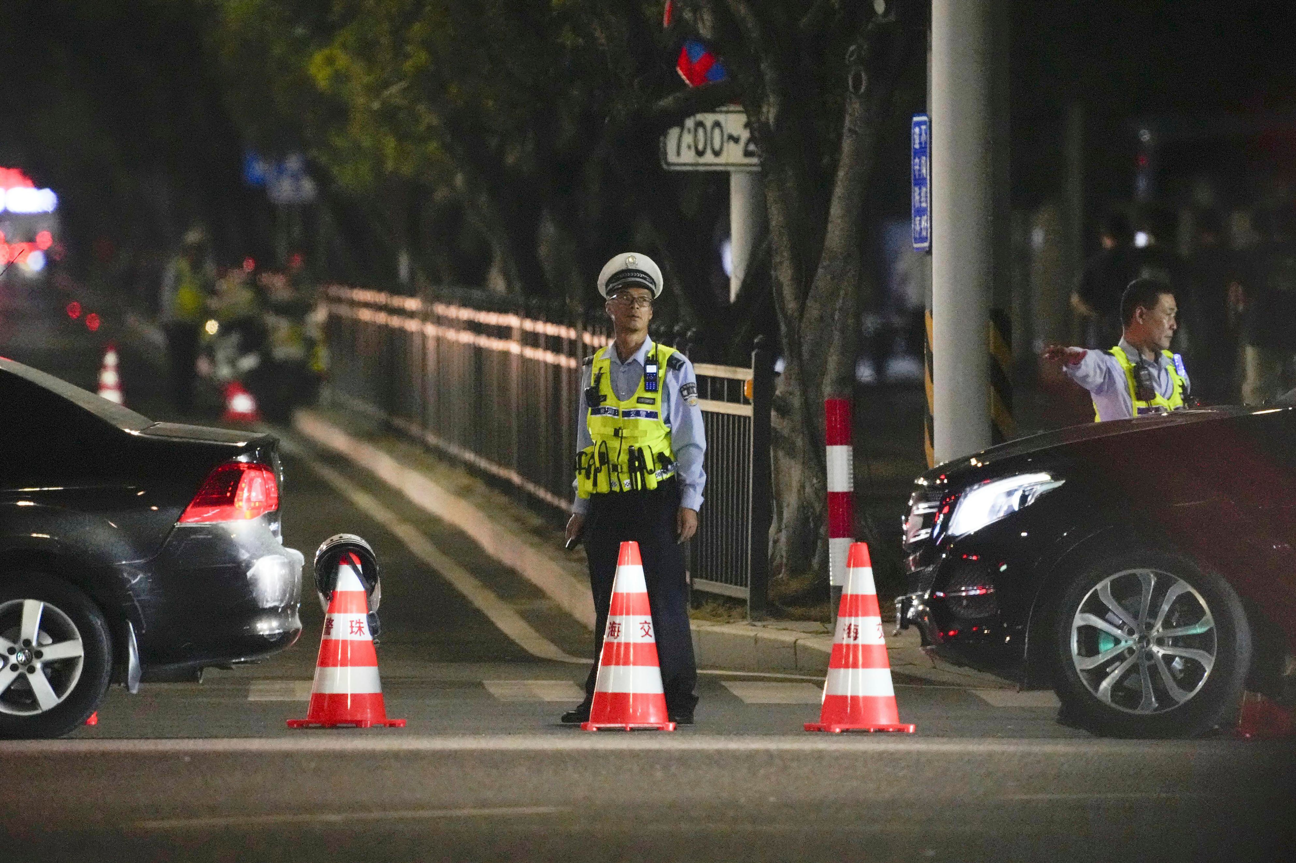 Una persona de seguridad hace guardia cerca de un centro deportivo donde un hombre embistió con un automóvil a personas que hacían ejercicio en Zhuhai, China, el lunes 11 de noviembre de 2024. (Kyodo News vía AP)