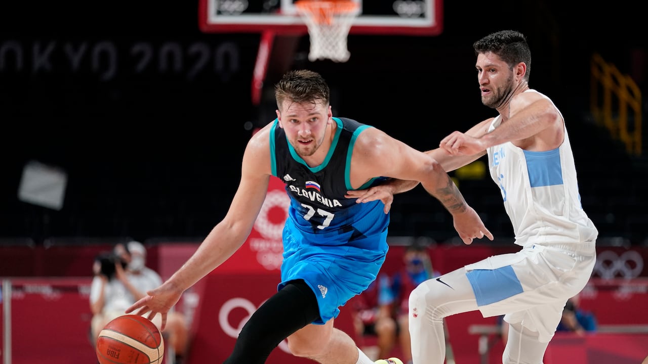 El esloveno Luka Doncic (77) avanza en la cancha por delante del argentino Patricio Garino (29) durante el juego de la ronda preliminar de baloncesto masculino en los Juegos Olímpicos de Verano de 2020, el lunes 26 de julio de 2021 en Saitama, Japón. (Foto AP / Charlie Neibergall)