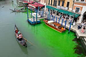 Una góndola navega por el histórico Gran Canal de Venecia, manchado por el líquido verde, el domingo 28 de mayo de 2023.