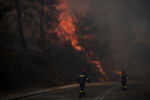 Bomberos inspeccionan las llamas cerca de una carretera en Varnava durante un incendio forestal, al norte de Atenas, Grecia, el domingo 11 de agosto de 2024. (Foto AP/Michael Varaklas)
