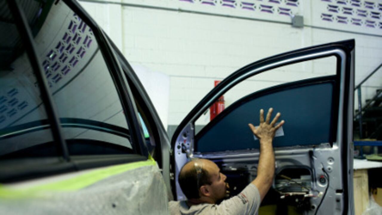 Un hombre instala un vidrio blindado en un carro en Venezuela.