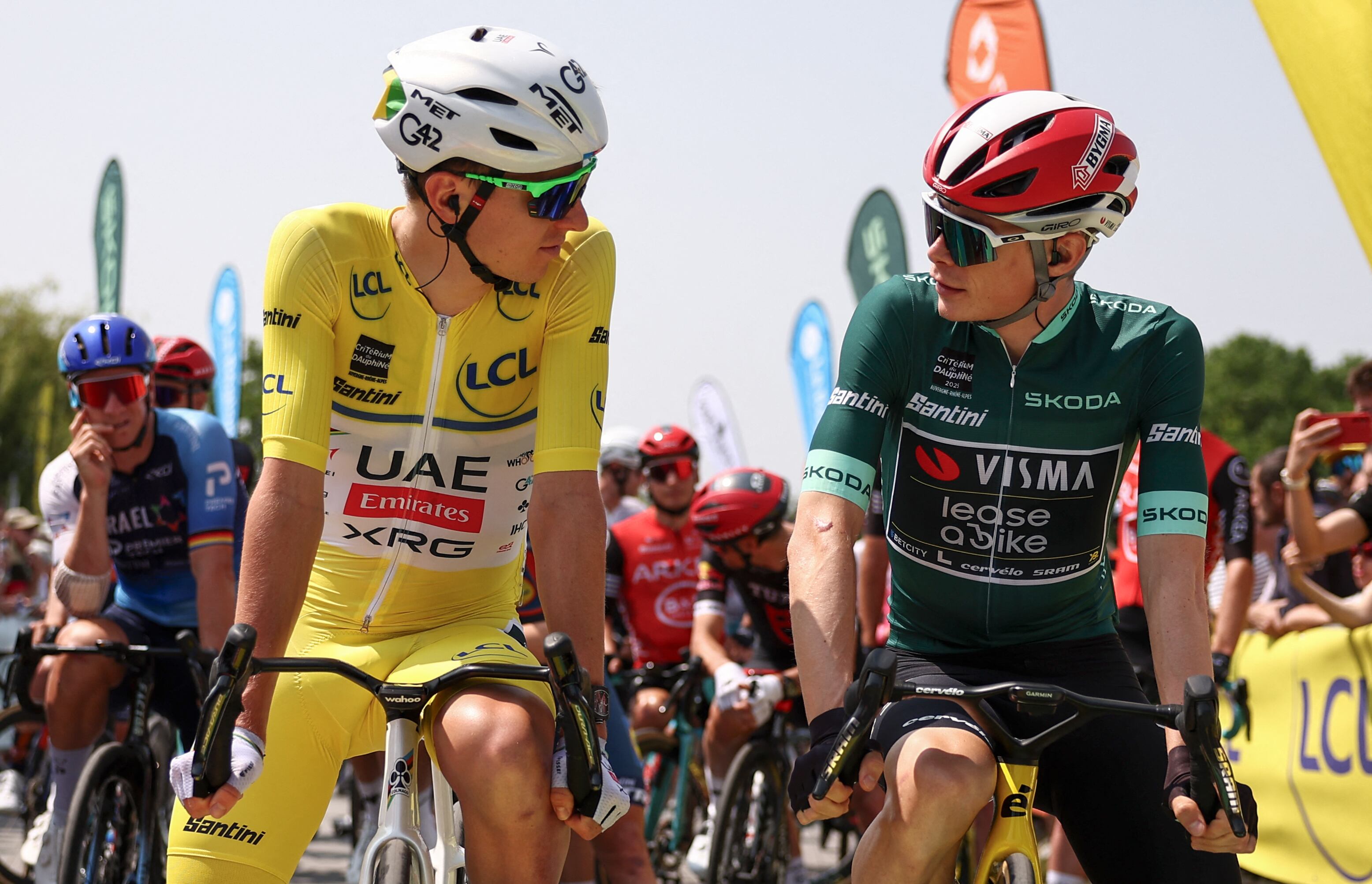 UAE Team Emirates XRG's Slovenian rider Tadej Poga?ar wearing the overall leader's yellow jersey (L) and Team Visma | Lease a Bike's Danish rider Jonas Vingegaard wearing the sprinter's green jersey look at each other prior to the start of the 2nd stage of the 77th edition of the Criterium du Dauphine cycling race, 204,6 km between Pr�milhat and Issoire, on June 9, 2025. (Photo by Anne-Christine POUJOULAT / AFP)