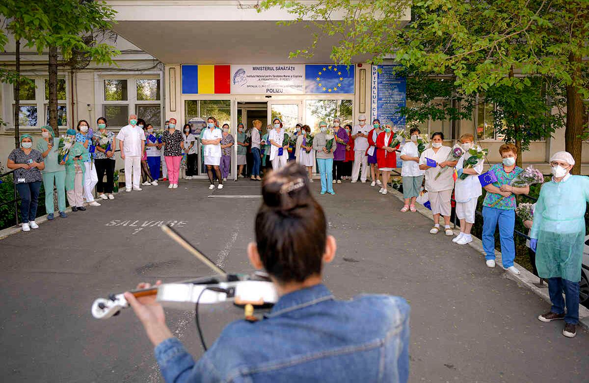 El personal médico del hospital de maternidad Polizu escucha a la violinista Raluca Raducana, quien toca para ellos y los pacientes, en Bucarest, la capital rumana. La joven artista mezcló piezas de rock y clásicas durante casi una hora. 28 de abril. Foto: Andreea Alexandru/ AP