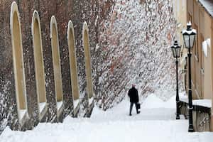Un hombre pasa junto a un muro cubierto de nieve después de una fuerte nevada en Praga, República Checa, el lunes 8 de febrero de 2021. Foto: AP / Petr David Josek.
