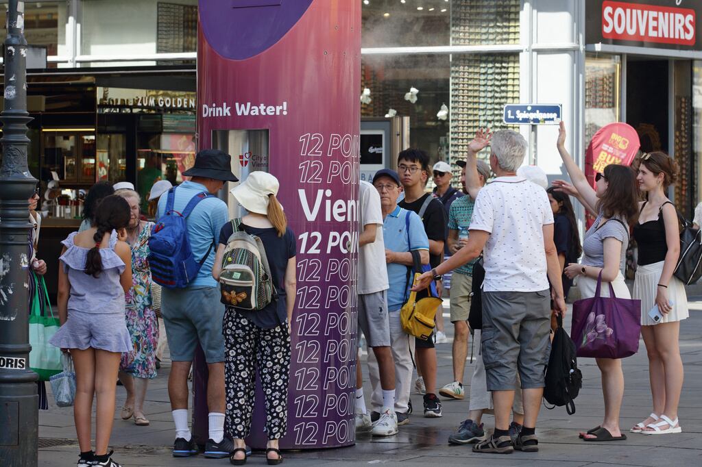 Varias personas forman una fila para rellenar botellas de agua en un caluroso día de verano en el centro de la ciudad de Viena, Austria.