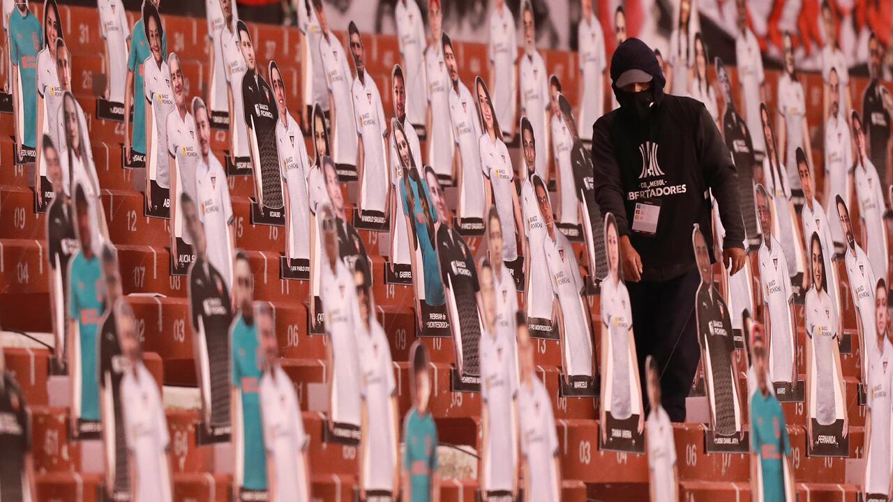 Un hombre camina en las gradas entre fotos recortadas de fanáticos en el estadio Casa Blanca antes del inicio de un partido de fútbol de la Copa Libertadores entre la Liga Deportiva Universitaria de Ecuador y el Sao Paulo de Brasil en Quito, Ecuador, el martes, Sept. 22, 2020. (Jose Jacome/Pool via AP)