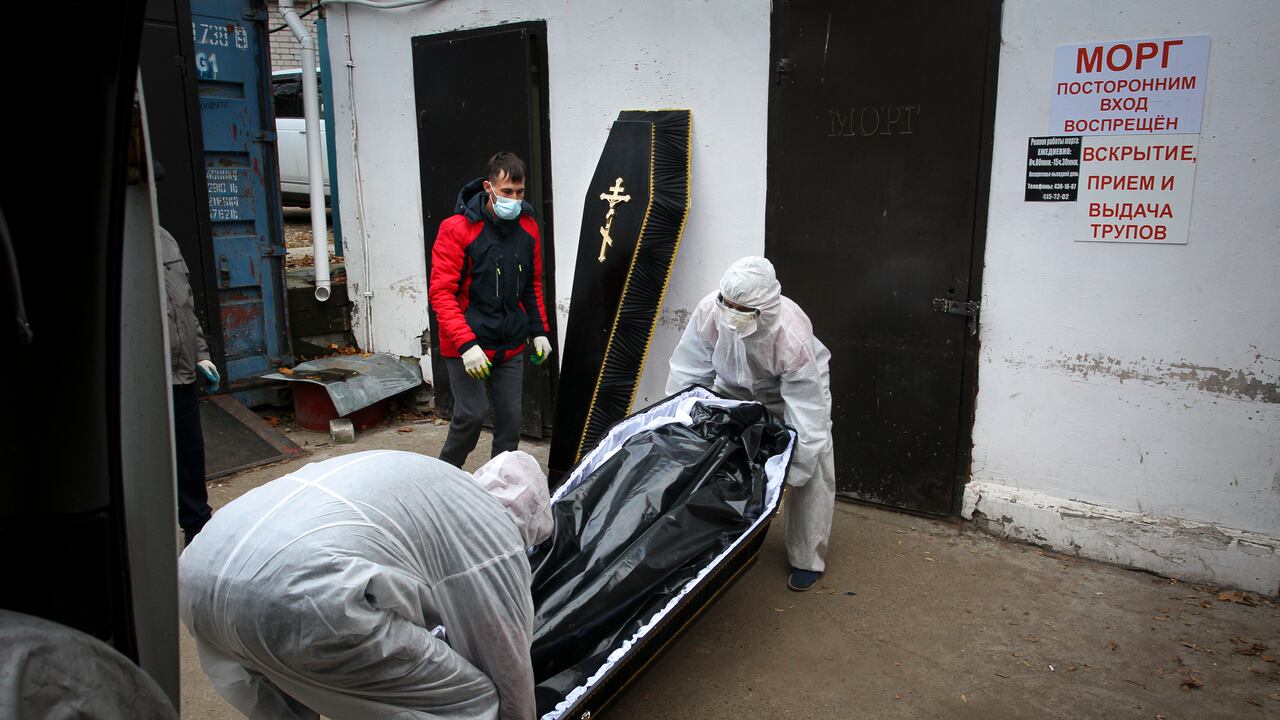 Medical workers in protective suits move a coffin with the body of a COVID-19 victim at the morgue of Infectious Hospital No. 5 in Nizhny Novgorod, Russia, on Wednesday, Oct. 20, 2021. The low vaccination rate in Russia, where only about a third of the population is fully vaccinated, is causing concern as the country suffers a sharp rise in cases, setting records for infections and deaths nearly every day this month. (AP Photo/Roman Yarovitcyn)