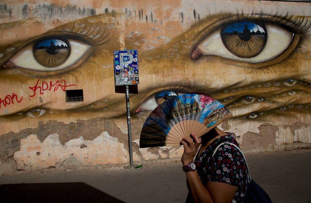 Una mujer pasa junto al mural del artista británico de la calle My Dog Sighs en el barrio de Trastevere de Roma, el lunes 24 de septiembre de 2018. (Foto AP / Alessandra Tarantino)