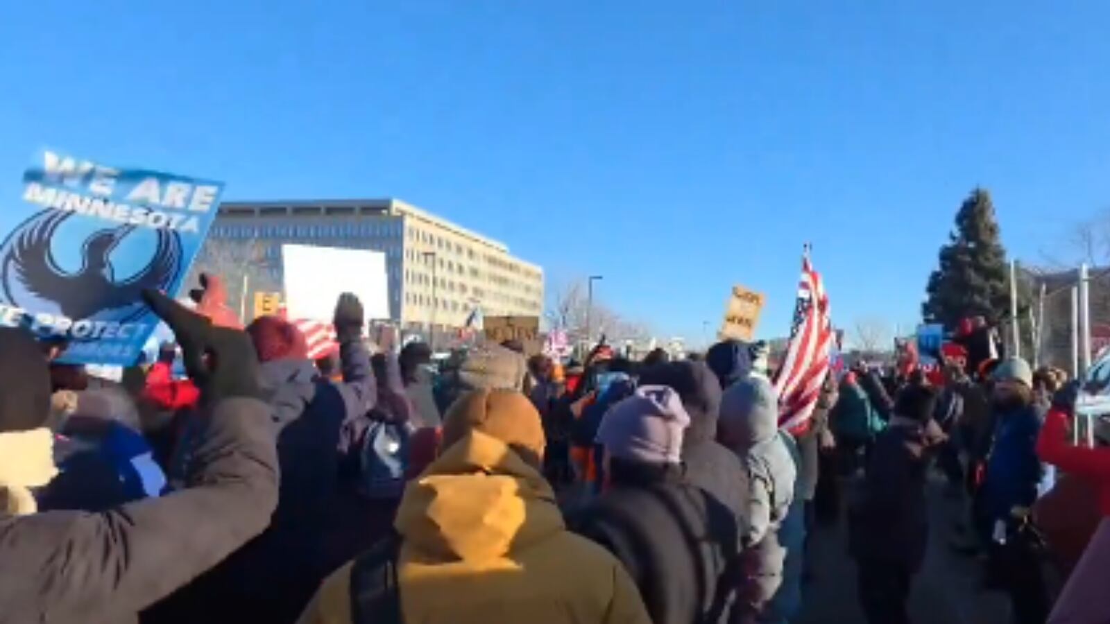 Manifestantes ocupan las calles frente al Edificio Whipple mientras los camiones de la Guardia Nacional permanecen estacionados.