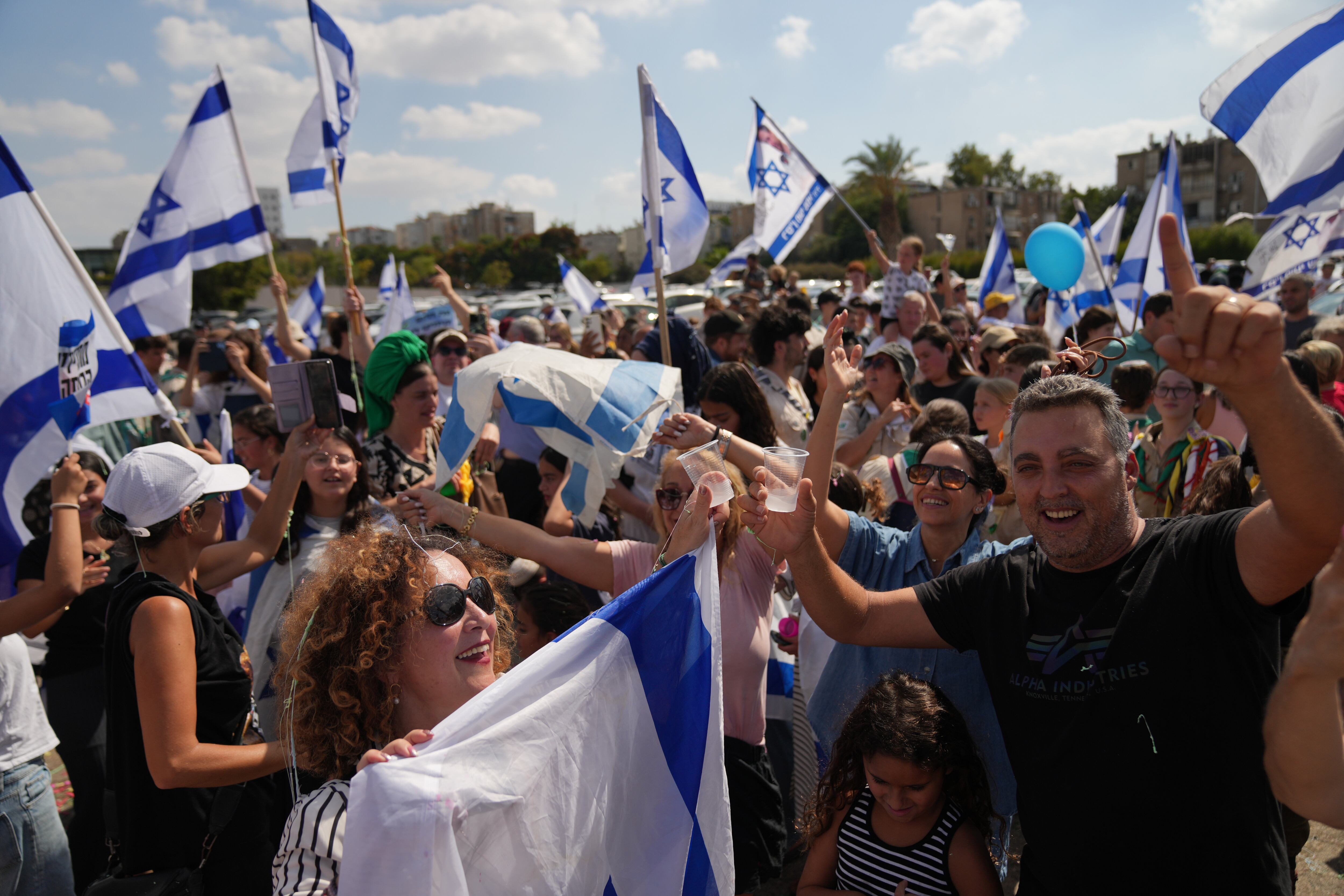 La gente ondea banderas israelíes en señal de celebración mientras esperan afuera del Hospital Beilinson en Petah Tikva, Israel, la llegada de algunos de los secuestrados liberados.