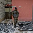 Un hombre ucraniano vestido de camuflaje se encuentra junto a bolsas para cadáveres cubiertas de nieve en el patio de una morgue en Mykolaiv, una ciudad a orillas del Mar Negro que ha estado bajo ataque ruso durante días el 11 de marzo de 2022. - El cadáver yace con su manos juntas, como en oración. De hecho, dice el empleado de la morgue, estaba lanzando cócteles molotov cuando los rusos lo atraparon. Le ataron las manos y lo ejecutaron. Tales son las escalofriantes imágenes de la morgue de Mykolaiv, una ciudad a orillas del Mar Negro que ha enfrentado días de ataque ruso. Afuera, en el patio del instituto forense donde se encuentra la morgue, la nieve cae constantemente sobre cadáveres envueltos en bolsas de plástico gris, que esperan ser evacuados. (Foto de BULENT KILIC / AFP)