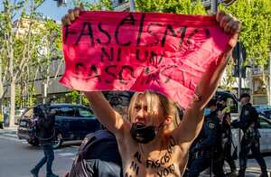 na integrante del grupo feminista FEMEN protesta con el pecho desnudo leyendo "Ni voto ni permiso al fascismo" levanta una pancarta que dice "Ni un paso más al fascismo" frente a la mesa electoral donde votará la candidata del partido de extrema derecha Vox, Rocío Monasterio durante las elecciones regionales para una nueva asamblea regional en Madrid, España, el martes 4 de mayo de 2021. Más de 5 millones de residentes de Madrid están votando el martes por una nueva asamblea regional en una elección que pone a prueba la profundidad de la resistencia a las medidas de cierre y la división entre la izquierda y partidos de derecha. Foto AP / Manu Fernandez.