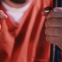 Hombre con las manos en las rejas de una cárcel