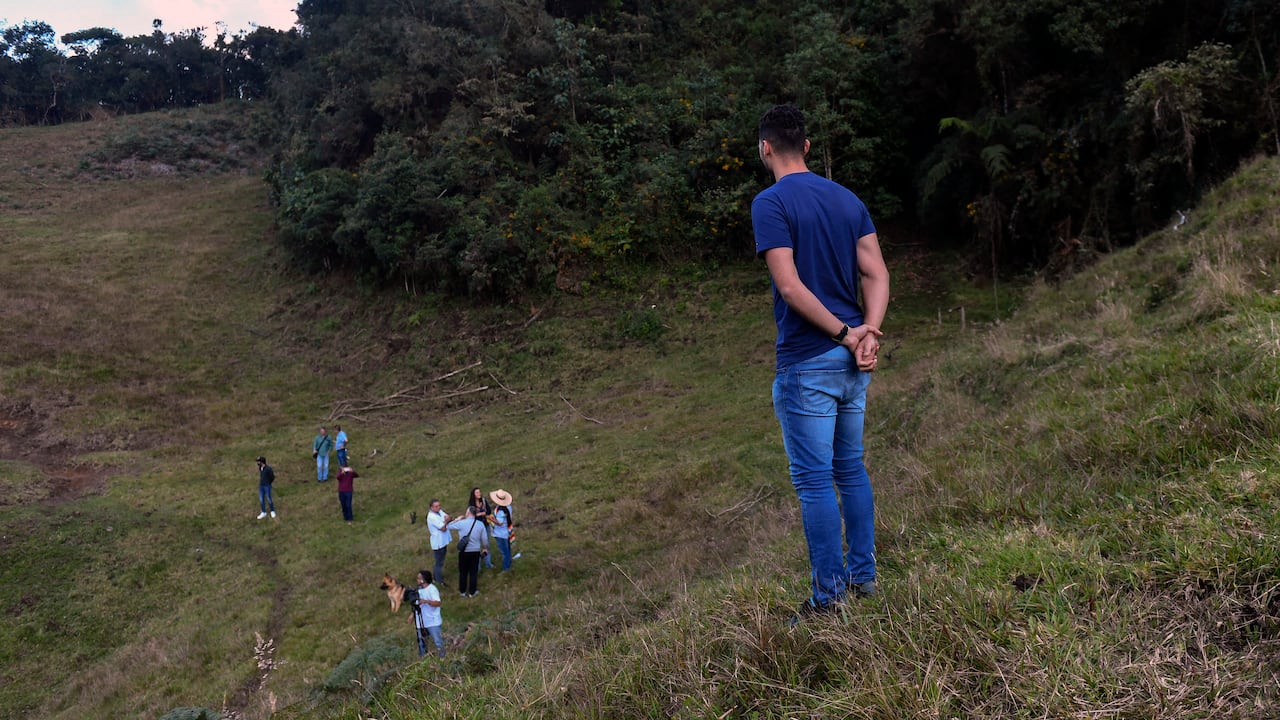 Former Brazilian football player Helio Neto (R) -a survivor of the Lamia flight 2933 plane crash that wiped out Brazilian football club Chapecoense- stands after planting a tree in tribute to the victims of the accidente at the Chapeco hill, on the fifth anniversary of the accident, near La Union, in Antioquia Department, Colombia, on December 1, 2021. - The plane was flying Chapecoense to Medellin to take on Atletico Nacional in the Copa Sudamericana finals -- the biggest and most unexpected game in the Brazilian team's history. When the plane ran out of fuel and went down in inhospitable mountains near its destination, 71 of the 77 aboard died, including 19 players. (Photo by JOAQUIN SARMIENTO / AFP)