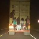Cinco personas colgadas de un camión.