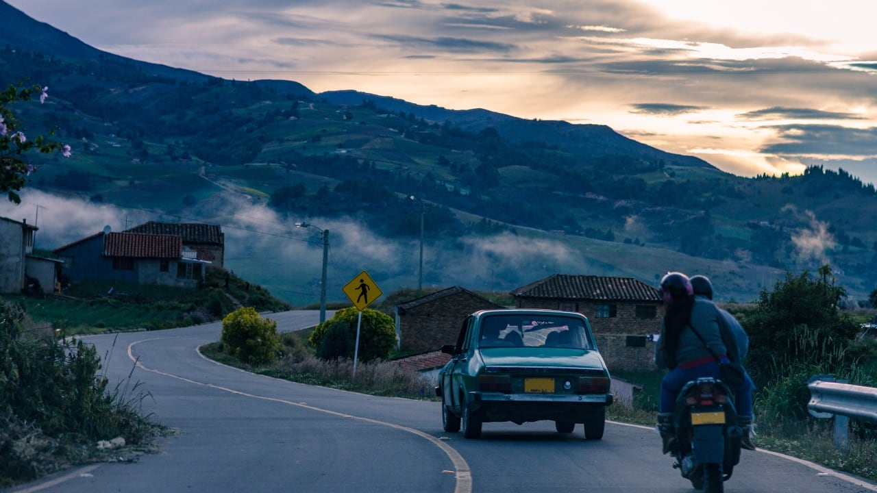 Automóvil y moto transitando en una carretera colombiana.