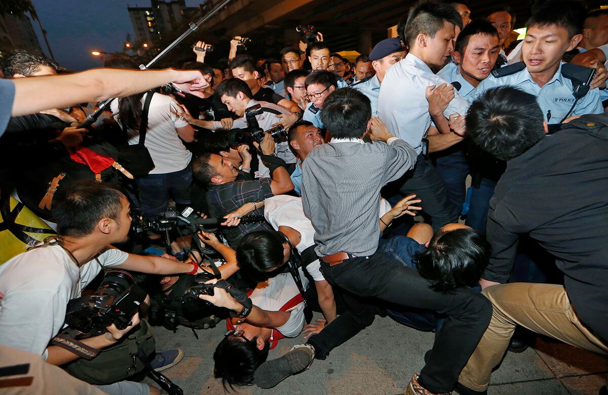 Los manifestantes prodemocracia y los fotógrafos caen al suelo luego de que fueran empujados por la policía mientras que el jefe ejecutivo de Hong Kong, Leung Chun-ying, se unía a una manifestación para apoyar la reforma del gobierno. (AP)