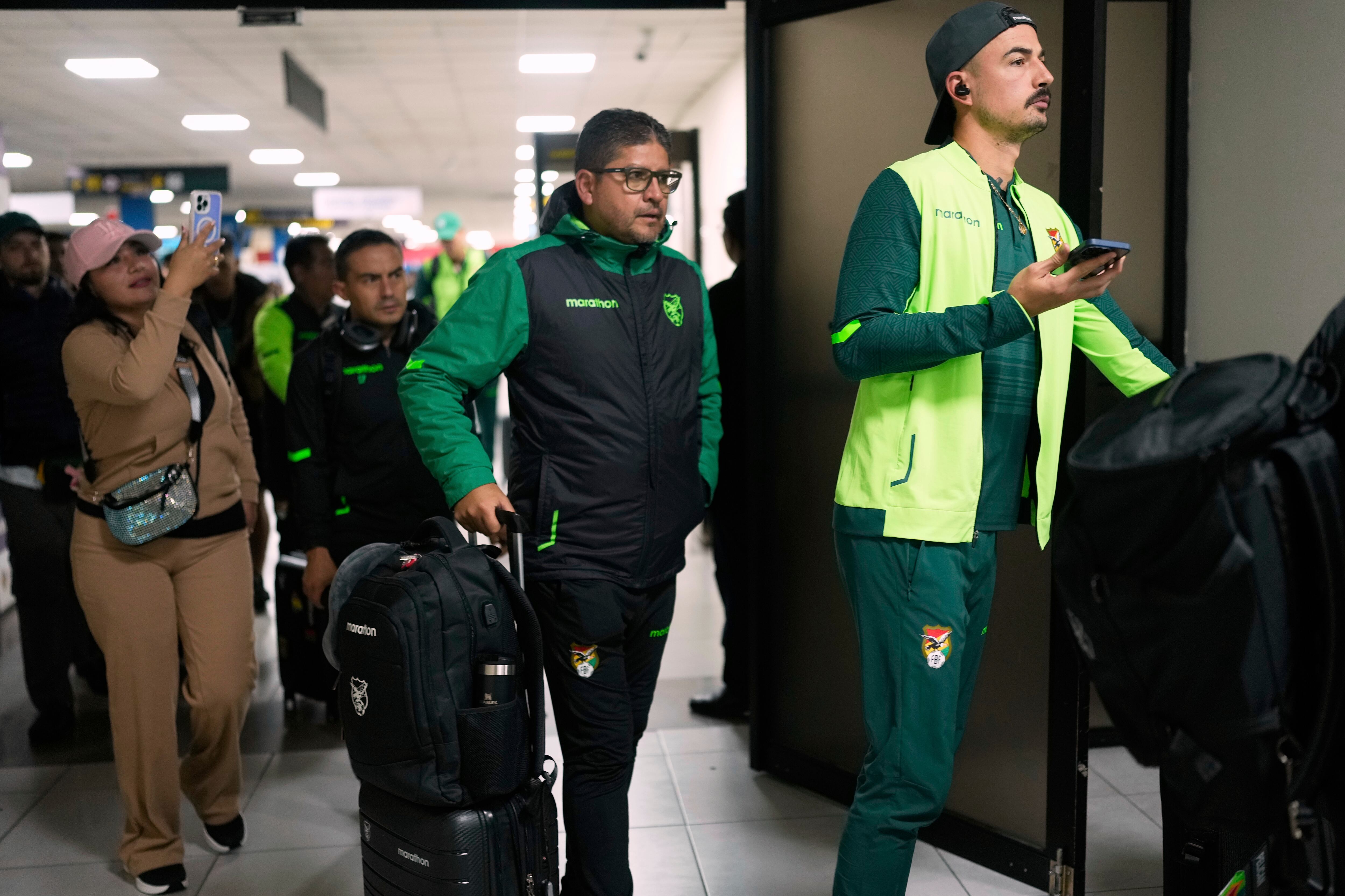 Bolivia's coach Oscar Villegas, center, and goalkeeper Guillermo Viscarra, arrive from Venezuela, at the airport in El Alto, Bolivia, Saturday, June 7, 2025, for their upcoming World Cup 2026 qualifying match against Chile. (AP Photo/Juan Karita)