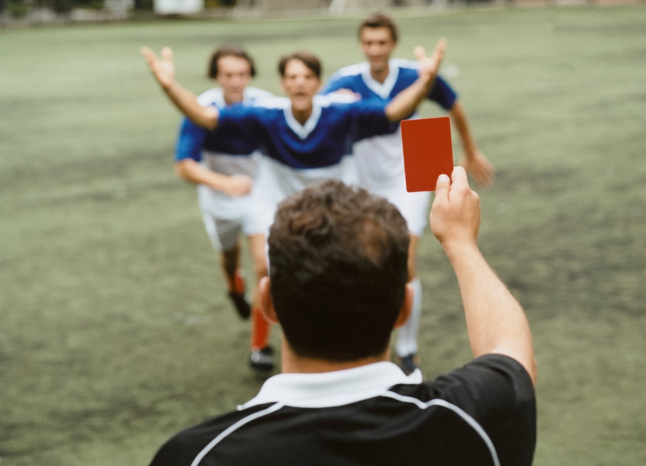 Árbitro mostrando tarjeta roja a jugadores