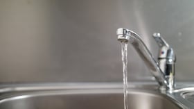 Agua que corre de un grifo a un fregadero. Fotografía de cerca