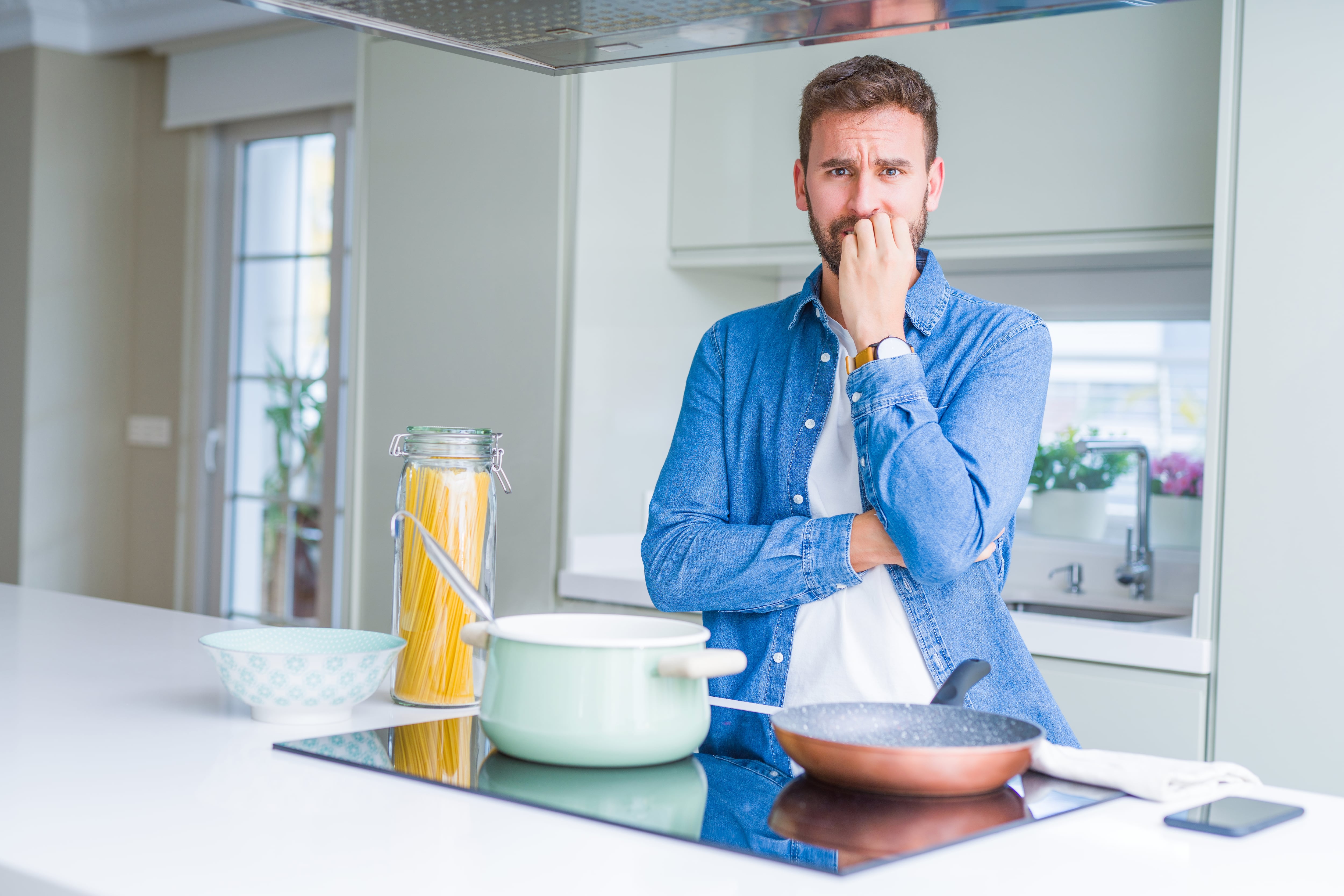 Hombre cocinando espaguetis italianos en la cocina, con aspecto estresado y nervioso.
