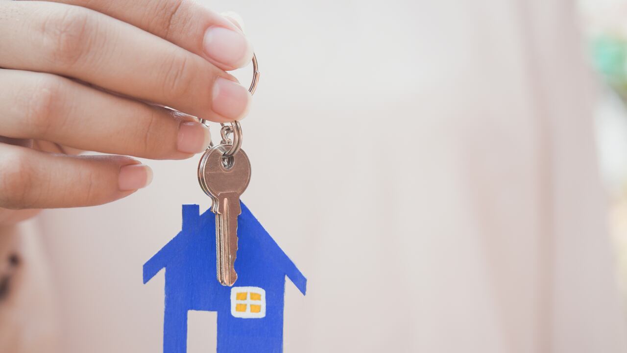 Mano femenina sosteniendo las llaves con la llave de la casa, agente inmobiliario.