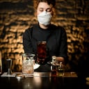 Foto de referencia de licor en medio de una mujer con tapabocas puesto