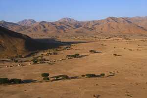 In the region of Sous Massa, near Tata, in south-eastern Morocco, stretches a desert plain of the Sahara Desert, near the Anti-Atlas mountain range at the foot of Jebel Bani. The desert advances little by little and sand dunes sometimes cover the palm trees of the great oasis.