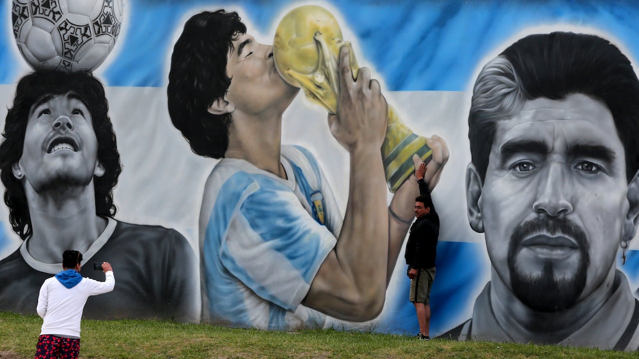 A man takes a picture of a mural honoring the late Diego Maradona in Santa Clara del Mar, Argentina, Saturday, Oct. 30, 2021, on the birth day of the soccer legend who died on Nov. 25, 2020 at the age of 60. (AP Photo/ Vicente Robles)
