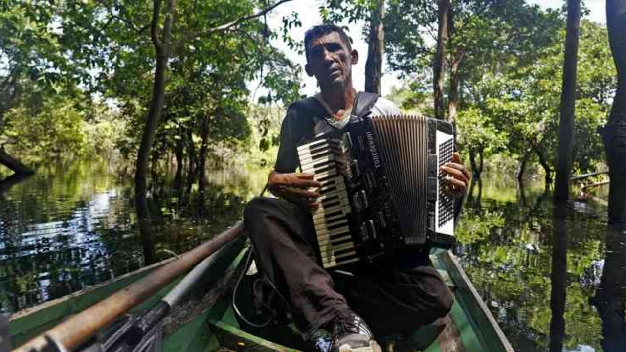 Solo en su modesta canoa de madera, "Eder el acordeonista", como se le conoce, se siente impotente ante la deforestación y la minería ilegal. Foto: Florence Goisnard / AFP