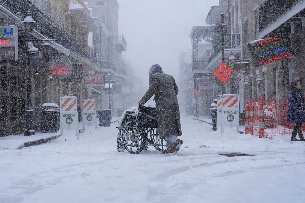 Una persona empuja una silla de ruedas en Bourbon Street durante una nevada, en Nueva Orleans, el martes 21 de enero de 2025. (AP Foto/Gerald Herbert)
