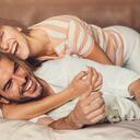 Feliz pareja joven juguetona en la cama.