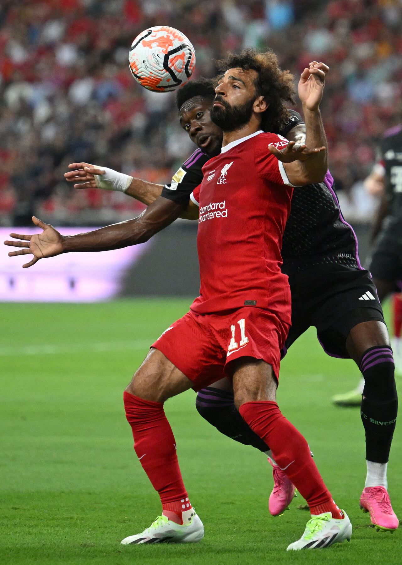 Liverpool's Egyptian striker Mohamed Salah (front) fights for the ball against Bayern Munich's Canadian midfielder Alphonso Davies during the Singapore Festival of Football pre-season friendly match in Singapore on August 2, 2023. (Photo by MOHD RASFAN / AFP)