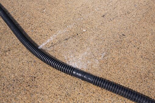 Acera mojada con salpicaduras de agua en el patio en un día soleado.