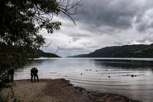 Los visitantes observan el agua del lago Ness, que está experimentando un nivel de agua inferior al promedio, el 6 de julio de 2023, en las Tierras Altas de Escocia.