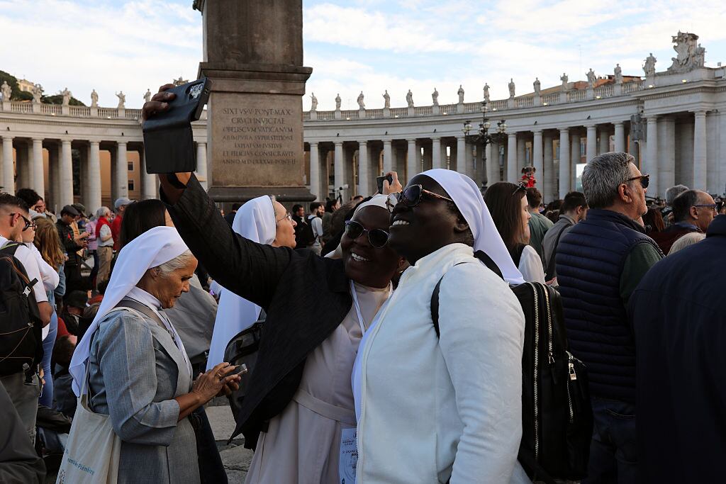 VATICAN CITY, VATICAN - MAY 7: Nuns pose for a selfie as people gather in St.Peter's square during the first day of Conclave on May 7, 2025 in Vatican City, Vatican. Cardinals of the Catholic Church have descended on Vatican City to commence the papal conclave, the secretive voting process held in the Sistine Chapel that requires a two-thirds majority to elect the new leader of the Catholic Church. The election follows the death of Pope Francis on April 21 at the age of 88. (Photo by Marco Di Lauro/Getty Images)