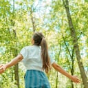 Mujer libre respirando aire limpio en el bosque de la naturaleza. Niña feliz desde atrás con los brazos abiertos en felicidad. Maderas frescas al aire libre, concepto de estilo de vida saludable de bienestar.