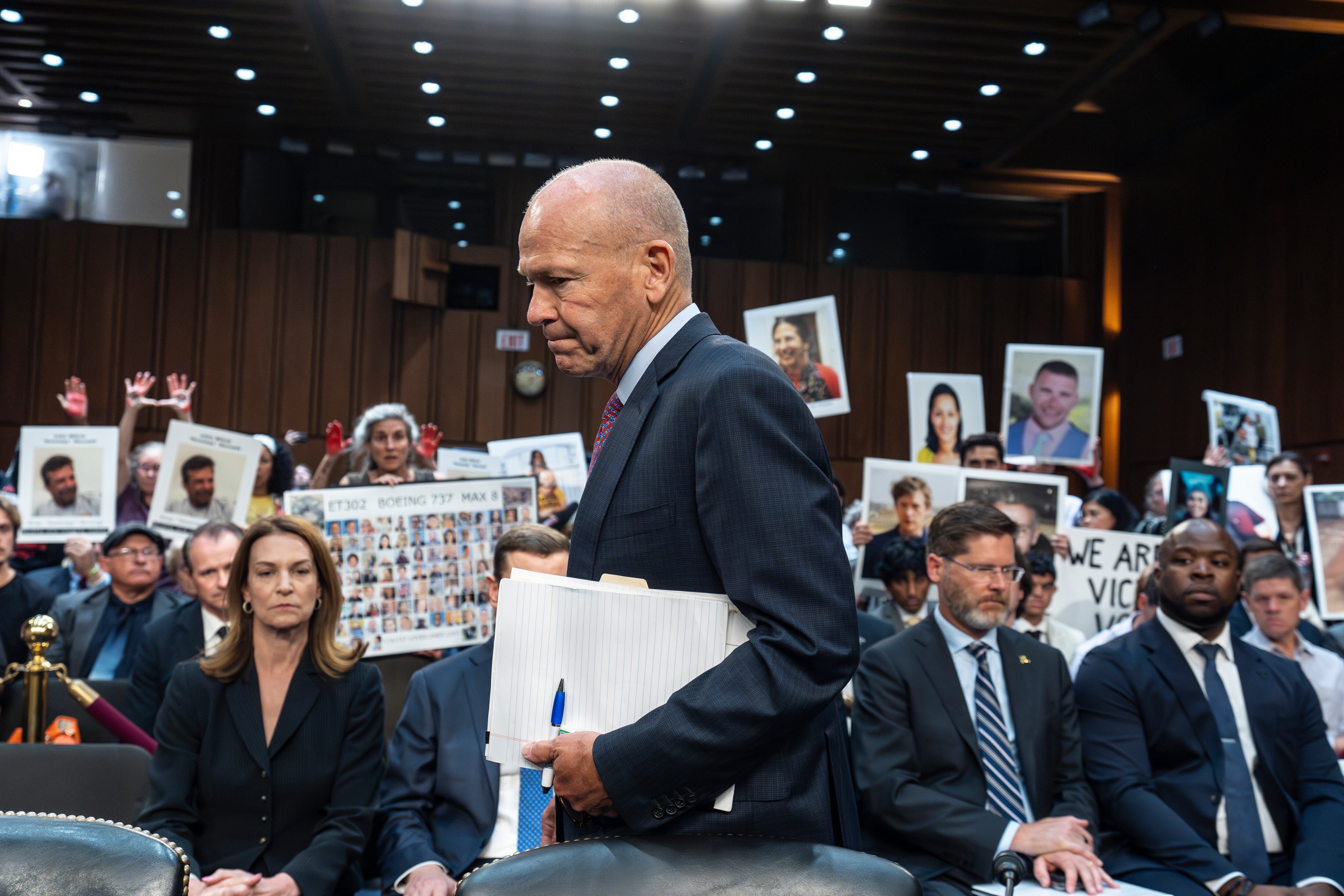 ARCHIVO - En una sala con manifestantes entre el público, el director general de Boeing, Dave Calhoun, llega al subcomité del Senado para responder a preguntas sobre problemas en la firma aeroespacial. (AP Foto/J. Scott Applewhite, Archivo)