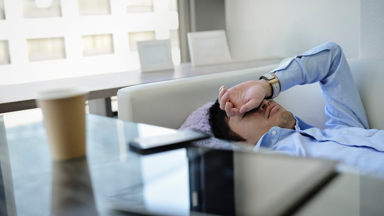 Hombre haciendo su siesta en un sofá, en medio de una jornada laboral