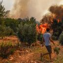 Un hombre camina frente a las llamas en la aldea de Kacarlar, cerca del poblado costero en el Mar Mediterráneo de Manavgat, Antalya, Turquía, el sábado 31 de julio de 2021. (AP Foto)