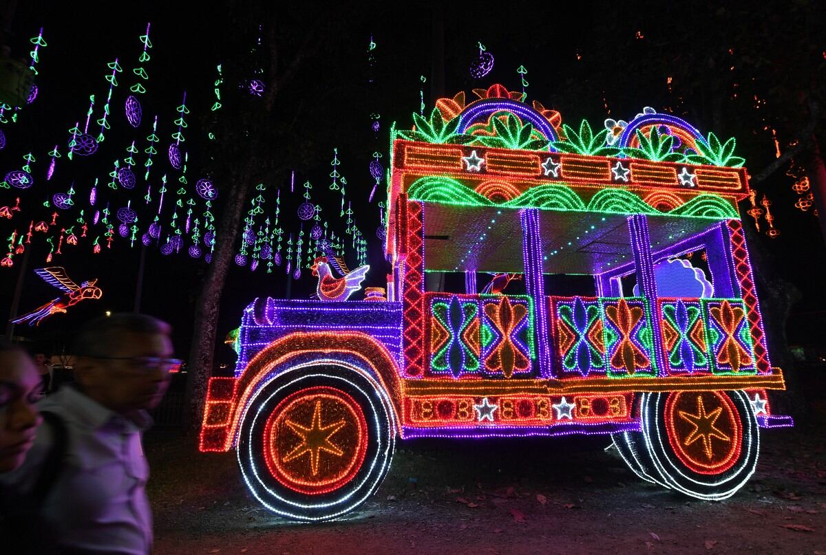 La gente pasa junto a un espectáculo de luces navideñas que representa un autobús chiva en Medellín, Colombia, el 27 de noviembre de 2025